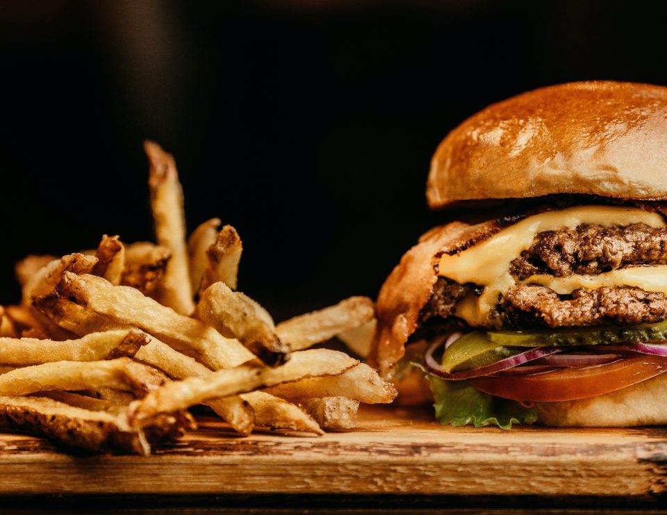 cheese burger with lettuce, pickles and onions and french fries on the side
