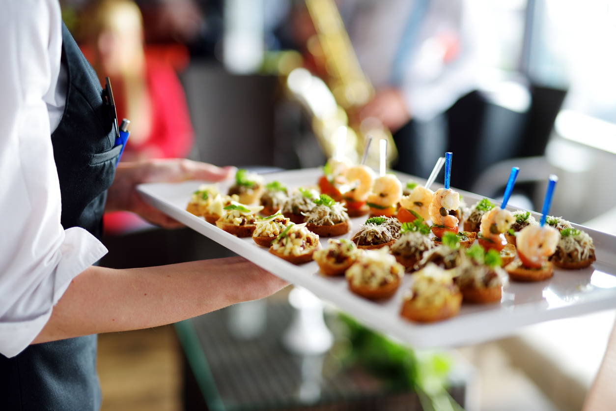 server holding tray of catered appetizers
