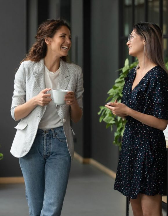 two women laughing while drinking coffee