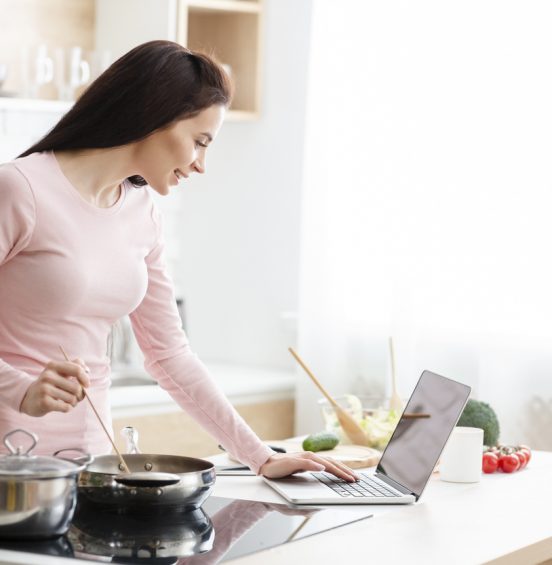 women on laptop stirring pot