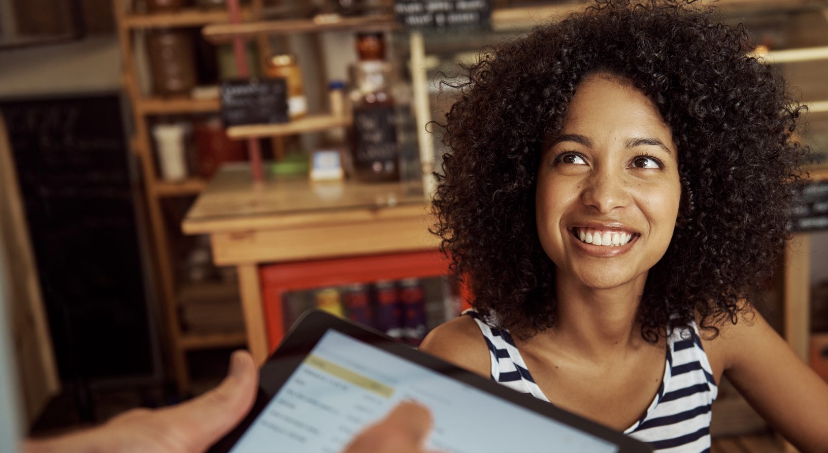 Shot of a beautiful woman smiling while a waiter is putting her order onto a digital tablet