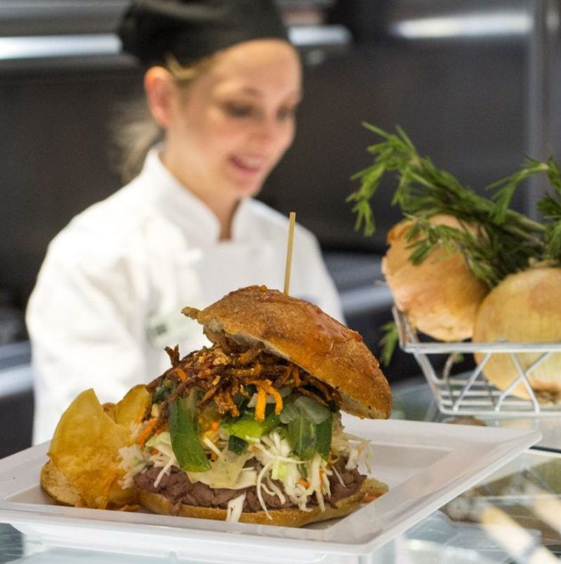 Sandwich awaits removal from kitchen after female chef finishes plating it